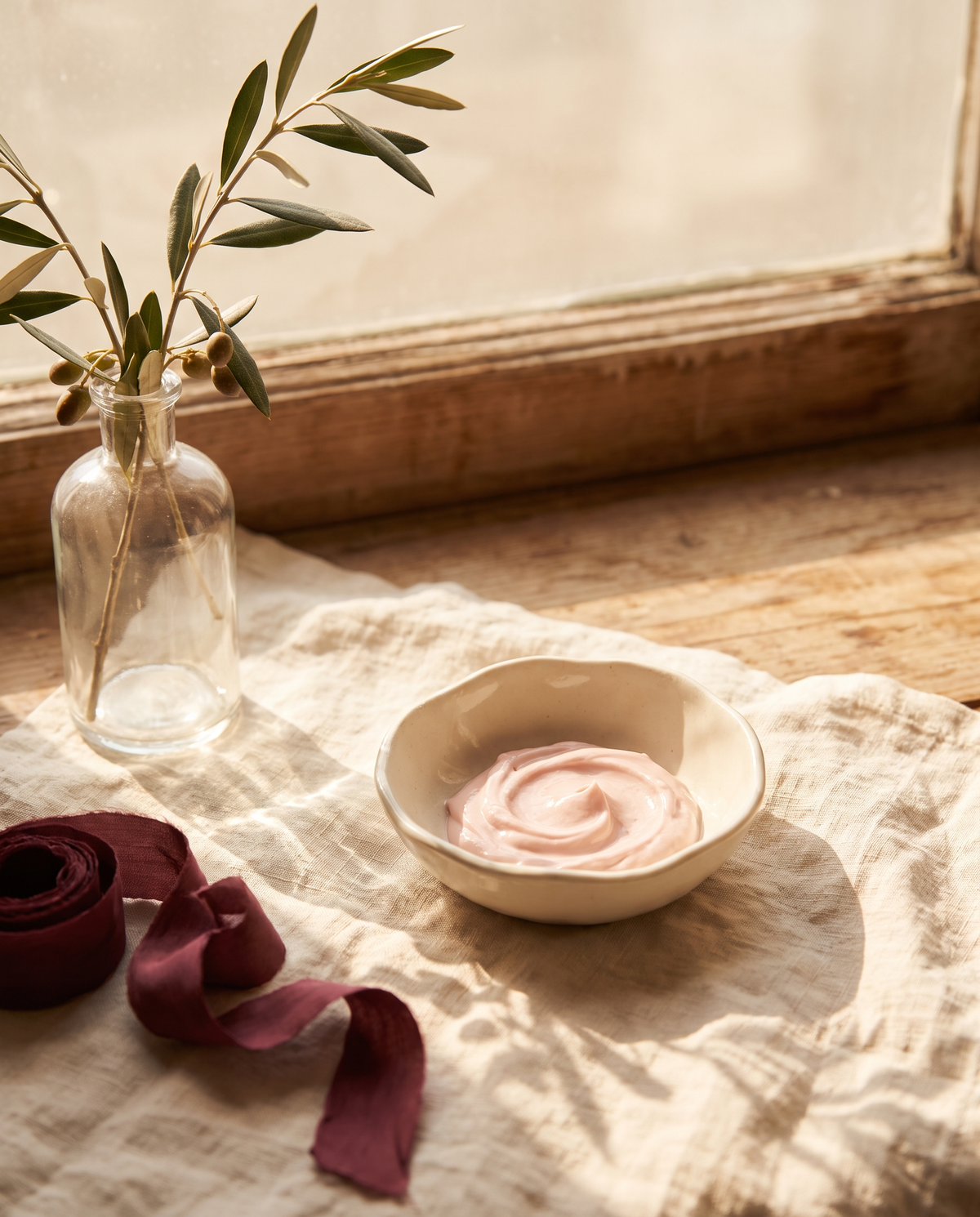 Manos sosteniendo un cuenco de cerámica con crema rosa